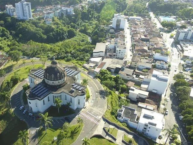 Vista aérea da Igreja Católica São José, com cúpula, cercada de árvores e dos bairros de Timóteo.