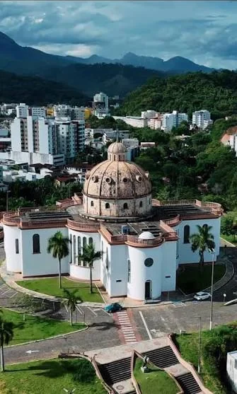 Igreja Católica São José vista do alto, com prédios e serras de Timóteo ao fundo.